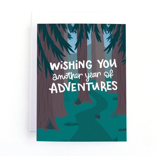 Hiking themed birthday card with the text, wishing you another year of adventures" over top an illustration of a hiking trail in the woods.