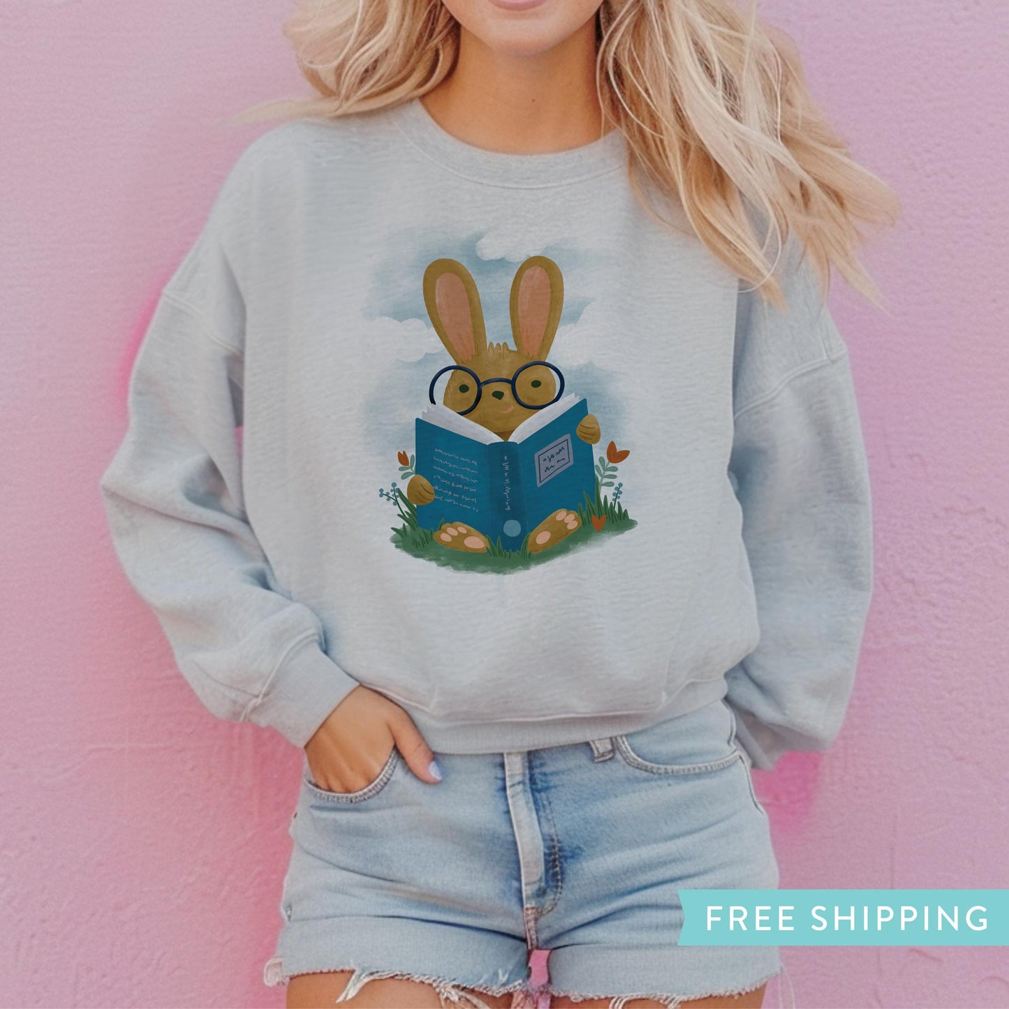 Women's Grey sweatshirt with an illustration of a bunny rabbit reading a book in a field of flowers.