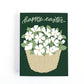 Easter card with an illustration of a basket full of white flowers and the message happy easter on a dark green background.