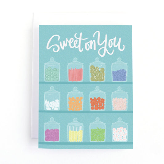 Love card featuring illustrations of shelves full of vintage jars of colourful candy on a blue background and the message, Sweet on You.