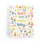 A baby shower card with the phrase 'that's one lucky baby' in colorful text, surrounded by a playful pattern of baby-themed illustrations including ducks, bows, and toys, shown with a white envelope on a white background.
