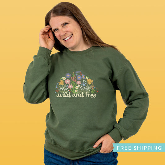 Woman wearing a green sweatshirt with floral design and 'wild and free' text