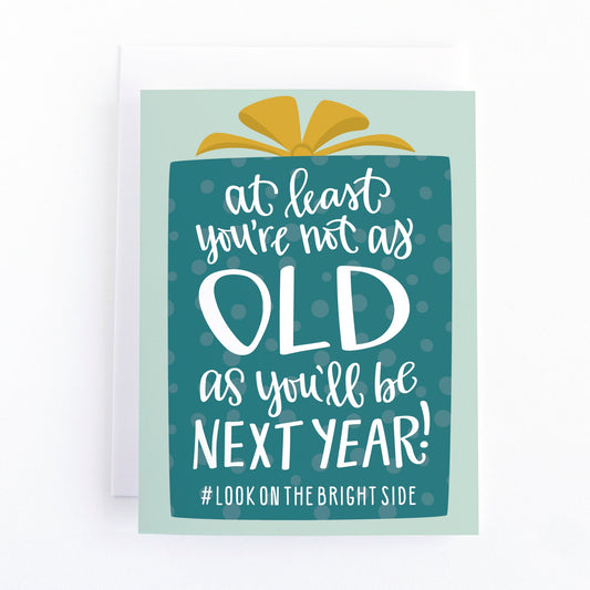 funny birthday card about getting older with hand lettered text on a wrapped gift with a bow