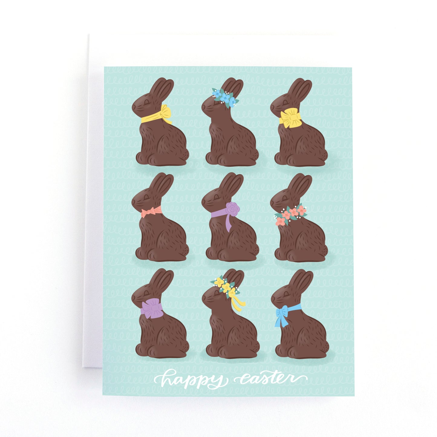 Easter card in modern pastels with illustrations of chocolate easter bunnies and the hand lettered greeting, happy easter