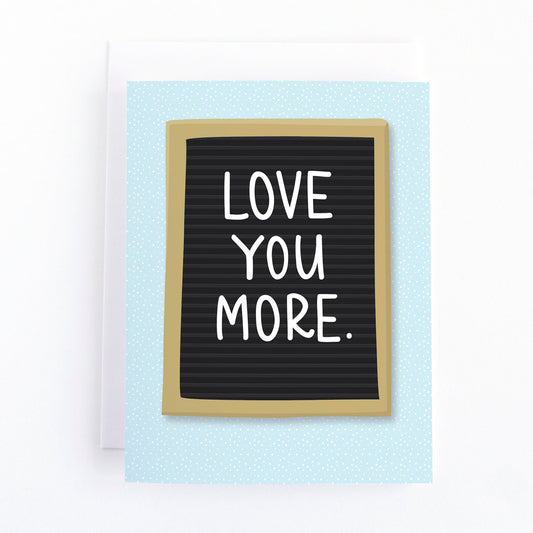 Valentines card with the message, Love you more written on a letterboard sign.