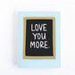 Valentines card with the message, Love you more written on a letterboard sign.