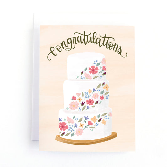 wedding card featuring a tiered wedding cake decorate with wild flowers and the hand lettered text, congratulations.