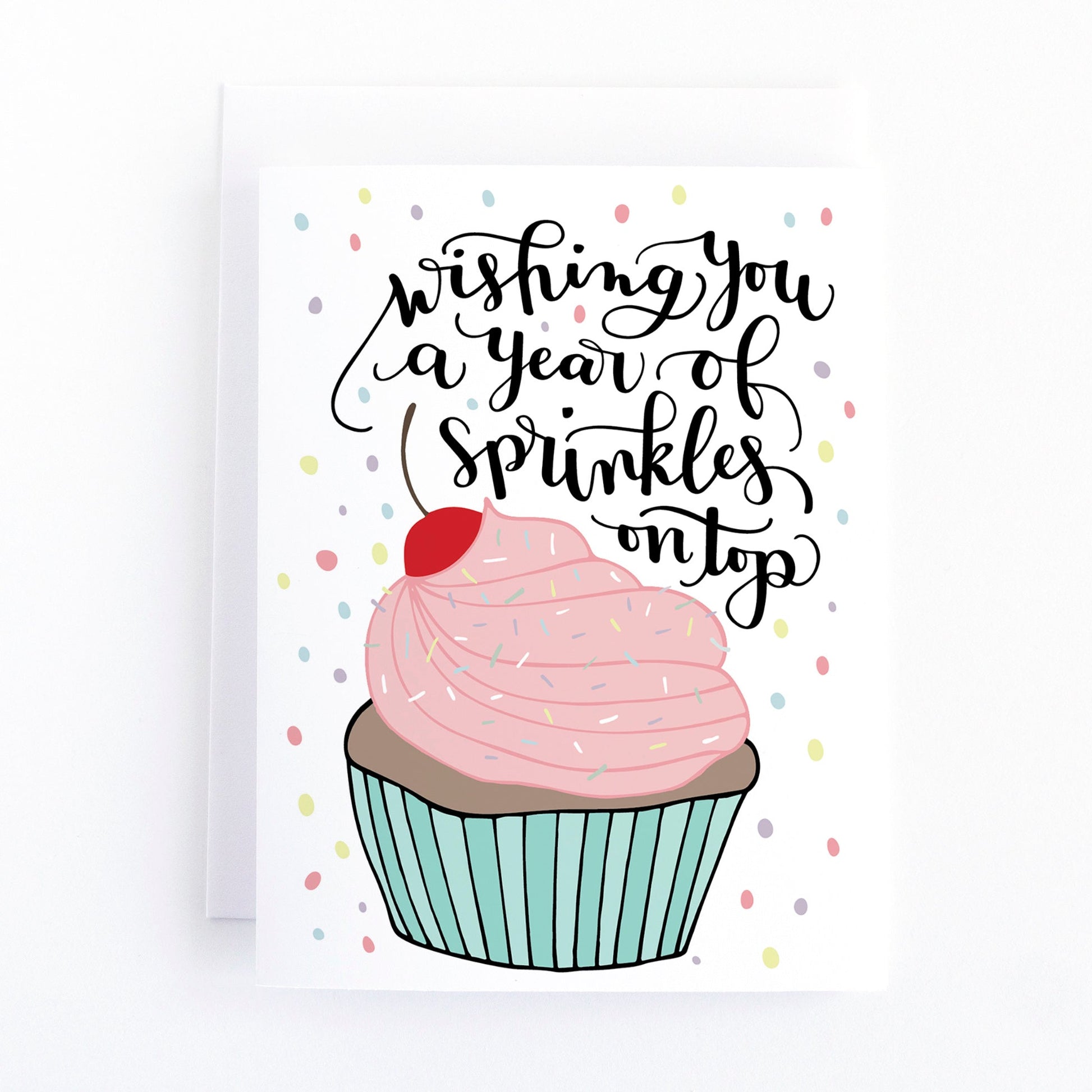 Birthday card with pink and blue cupcake that has sprinkles and cherry on top and a message that says wishing you a year of sprinkles on top.